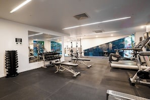 Ein modernes Fitnessstudio mit Laufbändern, Kraftgeräten und einer Spiegelwand.