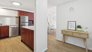 A modern kitchen with wooden cabinets, stainless steel appliances, and a dining area with a white table and chairs. - Oceanview 2BR apartment in the heart of Surfers Paradise (Surfers Paradise)
