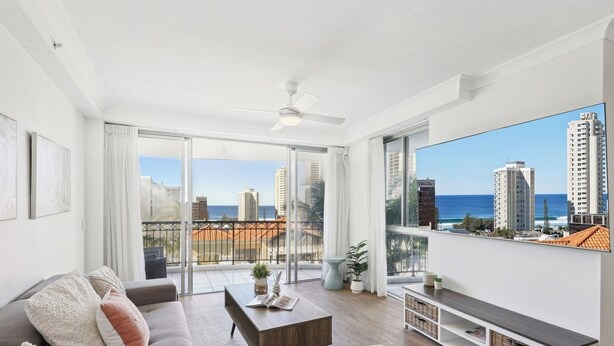 A modern living room with a sofa, coffee table, and a large TV screen. - Oceanview 2BR apartment in the heart of Surfers Paradise (Surfers Paradise)