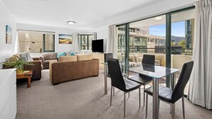 Een moderne hotelkamer met een zithoek, een glazen eettafel en een balkon met uitzicht op de stad.