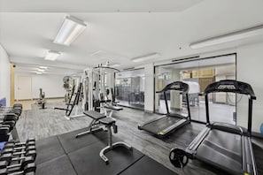 Kuntosali, jossa on juoksumattoja, painopenkkejä ja vapailla painoilla varustettu alue.