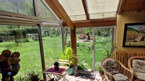 Una habitación luminosa con ventanas amplias, una mesa de comedor, sillas y plantas en macetas.
