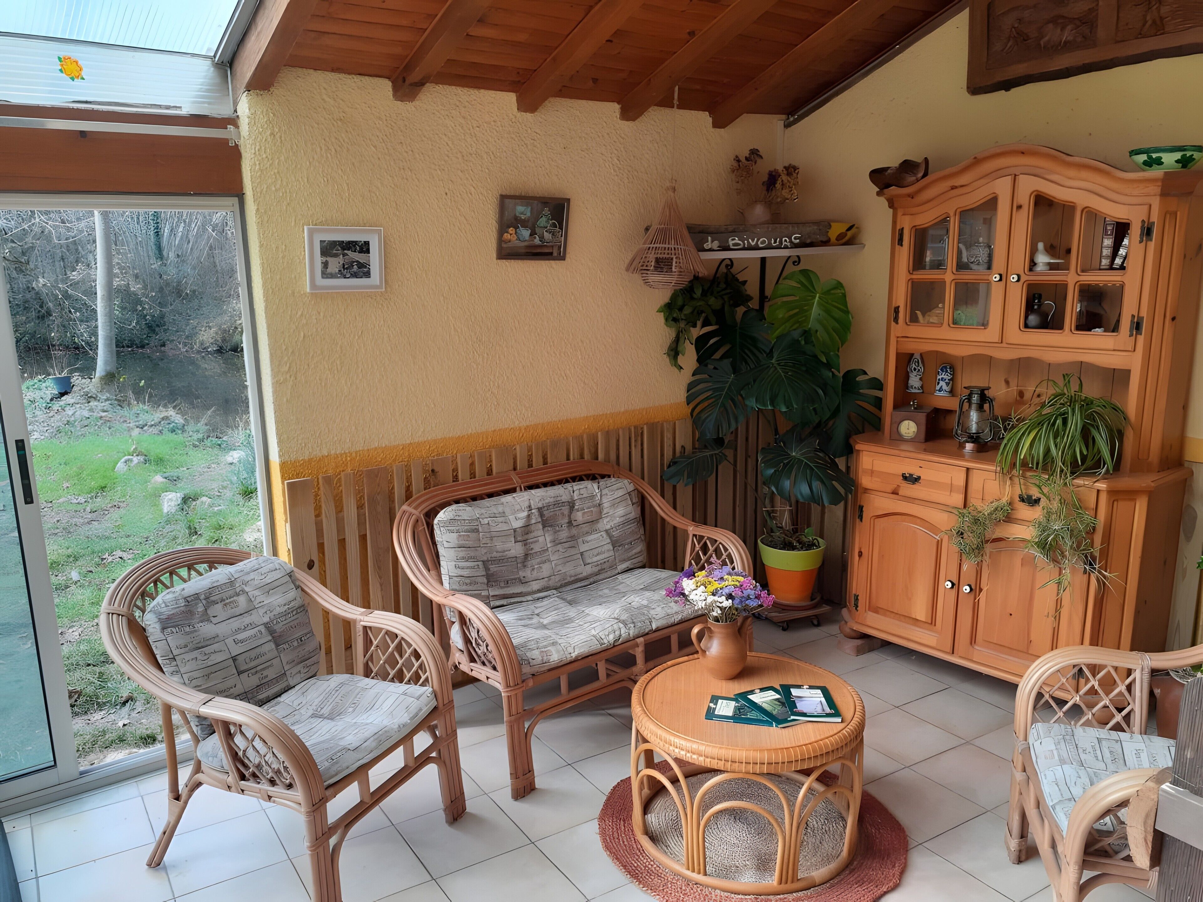 A cozy room with wicker furniture, a wooden cabinet, and a large potted plant.