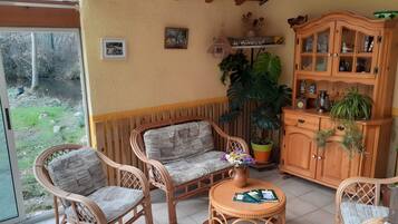 A cozy room with wicker furniture, a wooden cabinet, and a large potted plant.