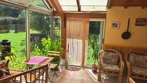 Un patio iluminado por el sol con una mesa, sillas y plantas en macetas.