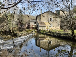 A house with a pond in front, surrounded by trees and a clear sky. - Holiday Home "Le Chant de la Rivière" – Exceptional and Unique Setting! (Carla de Roquefort)