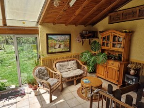 A cozy room with wicker furniture, a wooden cabinet, and a large window overlooking a garden. - Holiday Home "Le Chant de la Rivière" – Exceptional and Unique Setting! (Carla de Roquefort)