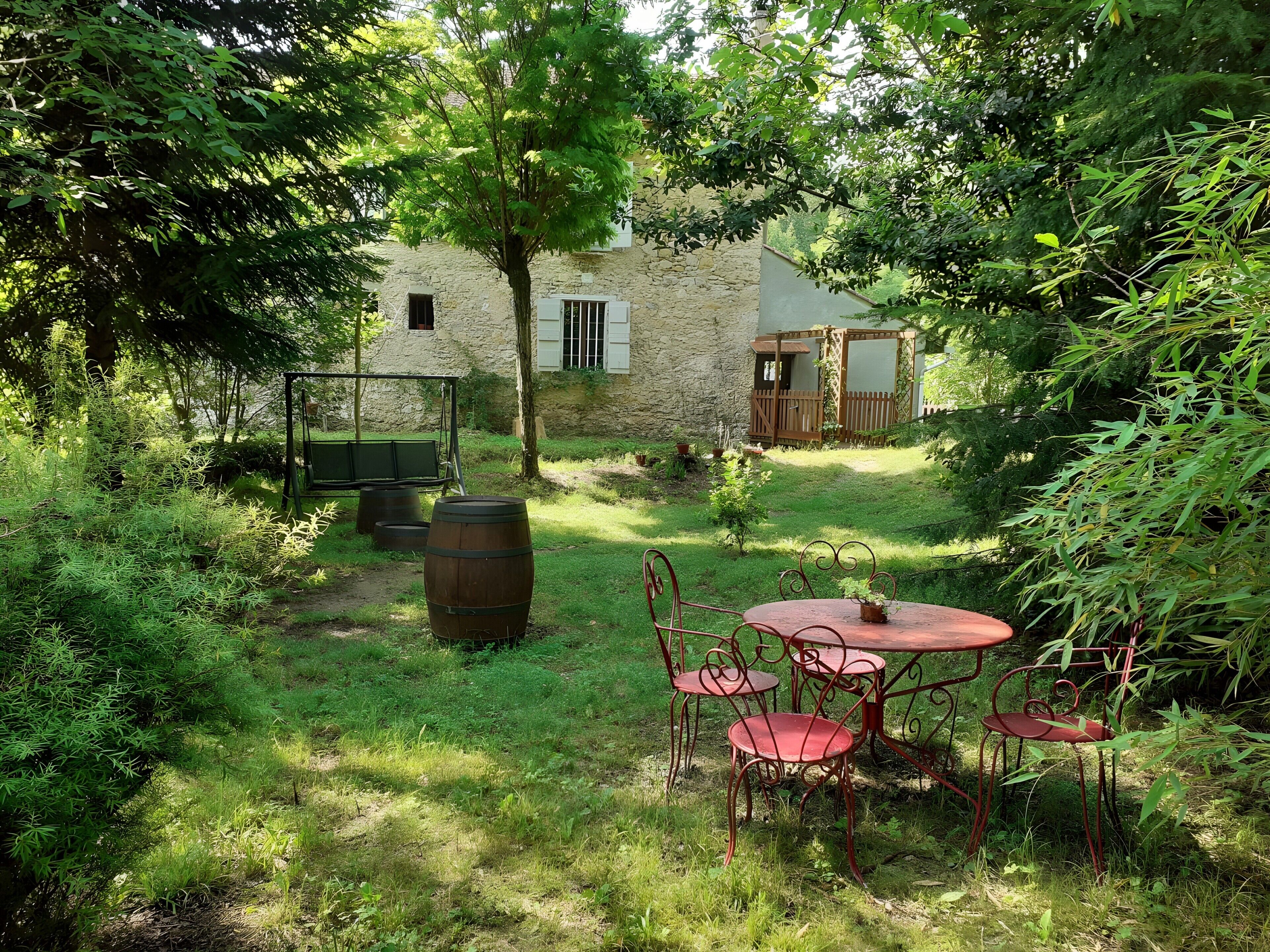 Un espace extérieur aménagé dans un style rustique, avec un bâtiment en pierre en arrière-plan.