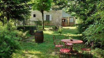 Un espace extérieur aménagé dans un style rustique, avec un bâtiment en pierre en arrière-plan.