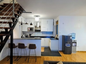 A compact kitchen with a built-in microwave, a stove, and a water dispenser.
