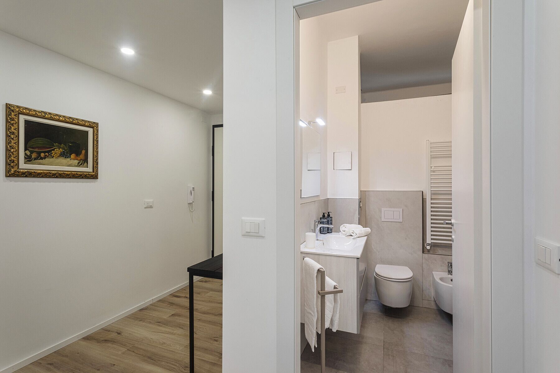 Et moderne badeværelse med toilet, vask og håndklædestang.