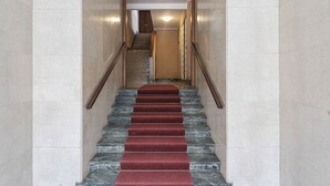 A staircase with a red carpet, marble walls, and wooden handrails. - Quinto Modern Flat by Wonderful Italy (Genoa)