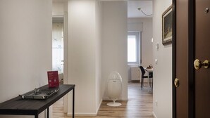 A hallway with a dining area in the background, a table with shoes, and a door with a picture frame. - Quinto Modern Flat by Wonderful Italy (Genoa)