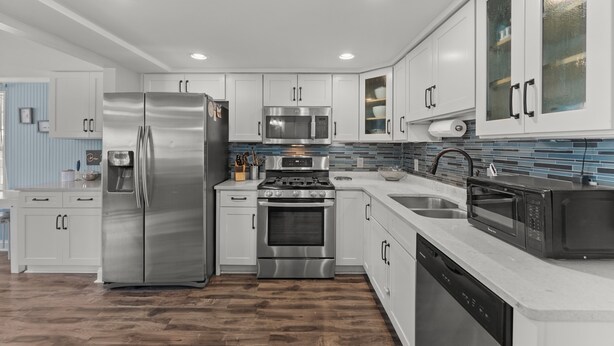 A modern kitchen with stainless steel appliances, white cabinetry, and a blue backsplash. - St. Augustine 3-bed, Walk to Beach, Pool, Hot Tub, Tiki & Golf Green (St. Augustine)