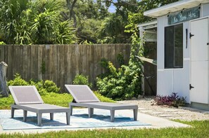 Two lounge chairs on a blue mat outside a building with a sign reading 'Ka Mori Huna'.
