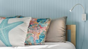 A bed with a white comforter, a wooden headboard, and two pillows with a floral pattern. - St. Augustine 3-bed, Walk to Beach, Pool, Hot Tub, Tiki & Golf Green (St. Augustine)