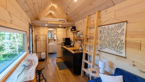 Un interior de cabaña funcional con cocina, comedor y un espacio de estar acogedor.