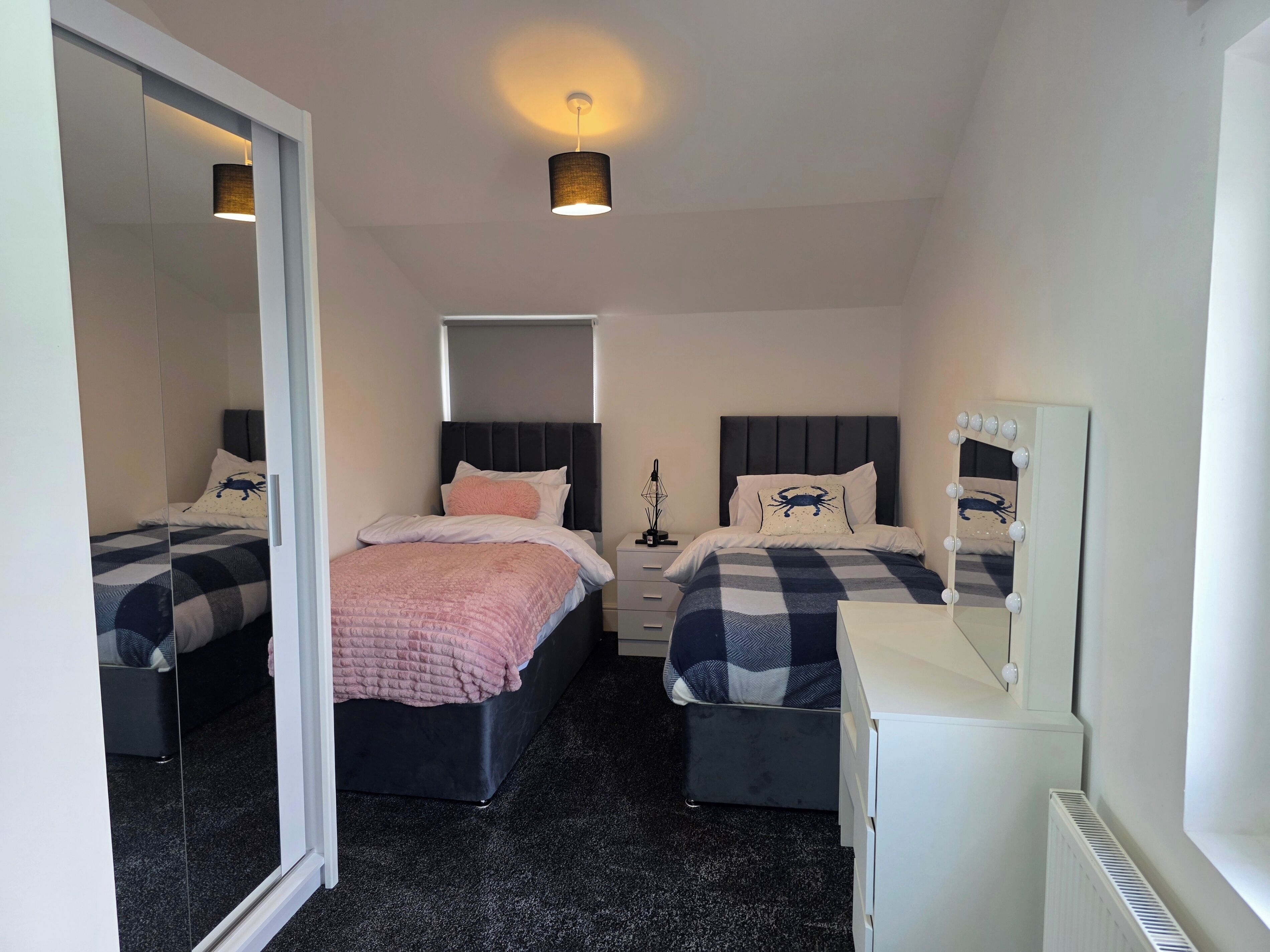 Un dormitorio con dos camas, un espejo y un aparador.
