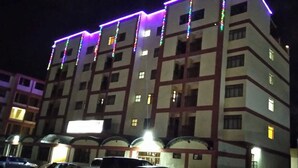 Un hôtel à plusieurs étages dont la façade, de style géométrique, est illuminée de lumières colorées.