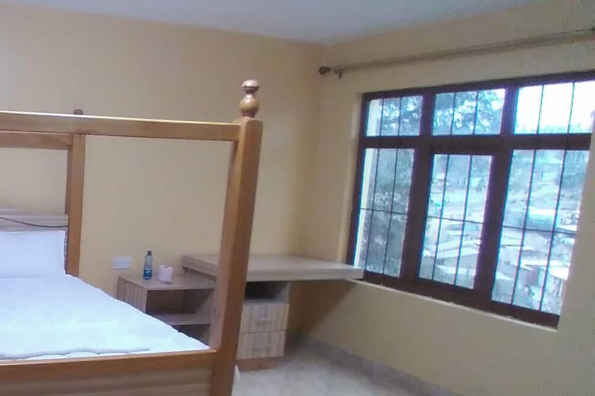 Uma cama com dossel em quarto de hotel, com janela e uma mesinha de cabeceira.