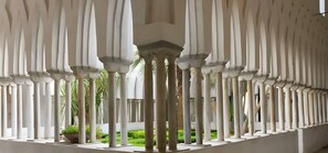 A series of white columns with a central open space, surrounded by greenery.