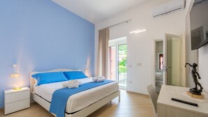 Ein Schlafzimmer mit einem Bett, Nachttischen, einem Schreibtisch, einem Sessel und einem Fernseher.