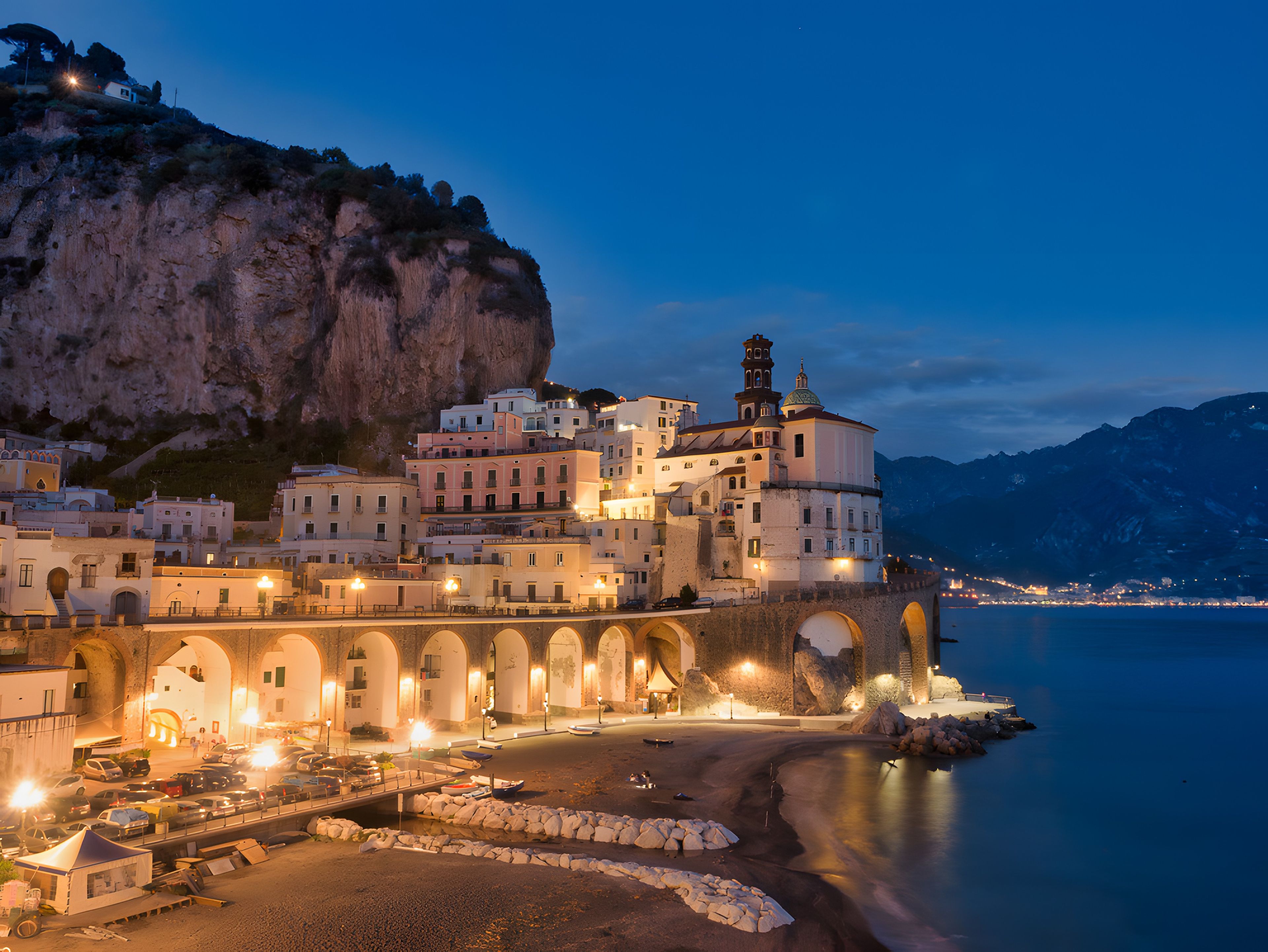 A coastal town with a prominent cliff, a bridge, and buildings with arched walkways.