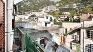 Eine Stadt an einem Hügel mit Gebäuden, ein Berg im Hintergrund und ein grünes Geländer.