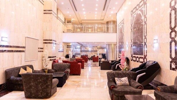 Un vestíbulo espacioso con varias zonas de estar, incluyendo sofás y sillones, y una silla de masaje.