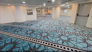 Un vestíbulo amplio con alfombra estampada y varias columnas.