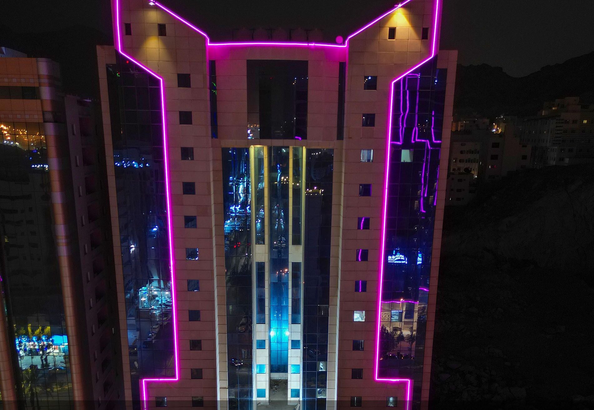 Een modern gebouw met roze neonverlichting dat de structuur accentueert.