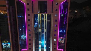A modern building with pink neon lights outlining its structure. - Al-Qemma Hotel (Makkah)