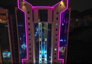 A modern building with pink neon lights outlining its structure. - Al-Qemma Hotel (Makkah)