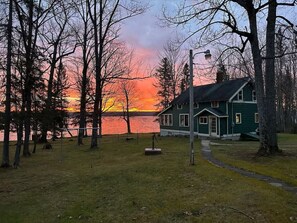 A house with a dock by a lake during sunset.