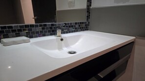A bathroom with a white sink, a mirror, and a tiled backsplash.