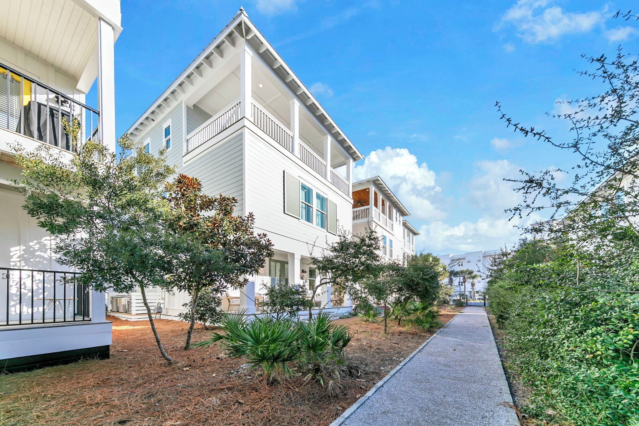 A modern two-story building with balconies, surrounded by well-maintained landscaping and a paved walkway.
