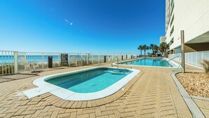 Un espace piscine avec vue sur l’océan, une chaise longue et un panneau indiquant qu’il est interdit de se baigner.