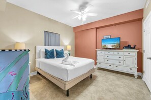 A bedroom with a bed, a dresser, a ceiling fan, and a television on the dresser.