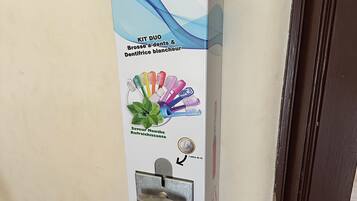 Een wandbevestigde dispenser met hendel, muntgleuf en een slot.