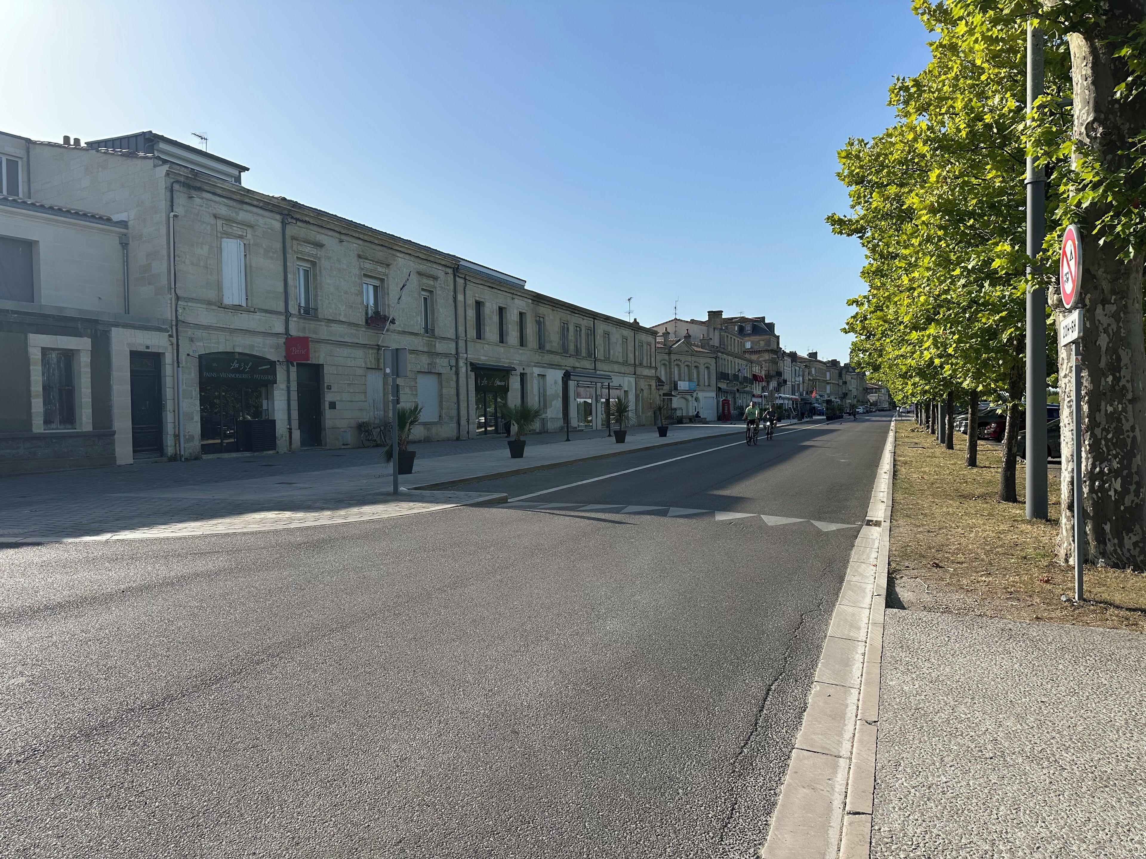 Une rue bordée d’immeubles, un panneau indiquant l’interdiction de se garer et un ciel dégagé.