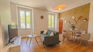 A modern living room with a sofa, chairs, a TV, and a dining table.