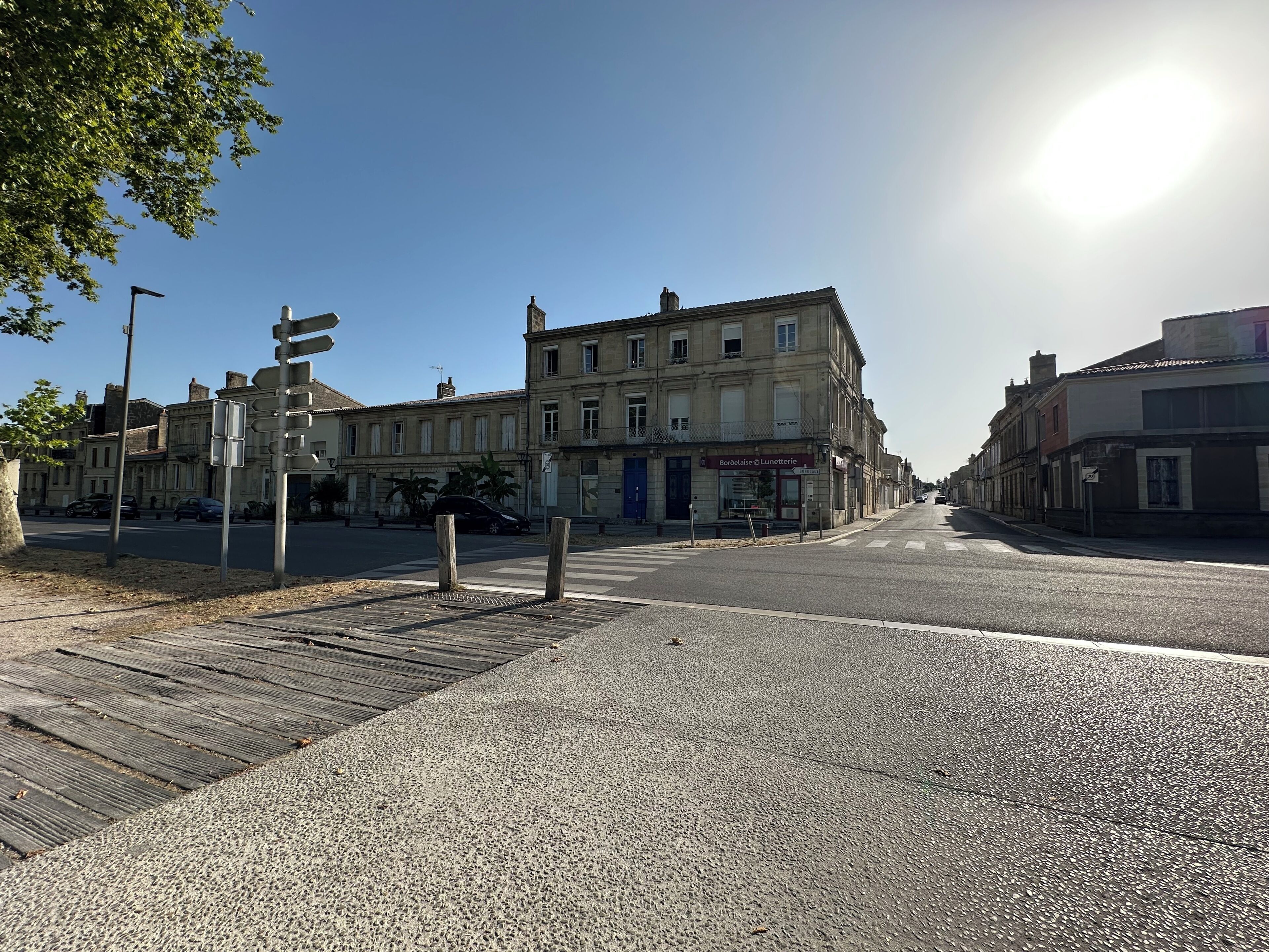 Straßenansicht mit Gebäuden, blauem Himmel und strahlender Sonne.