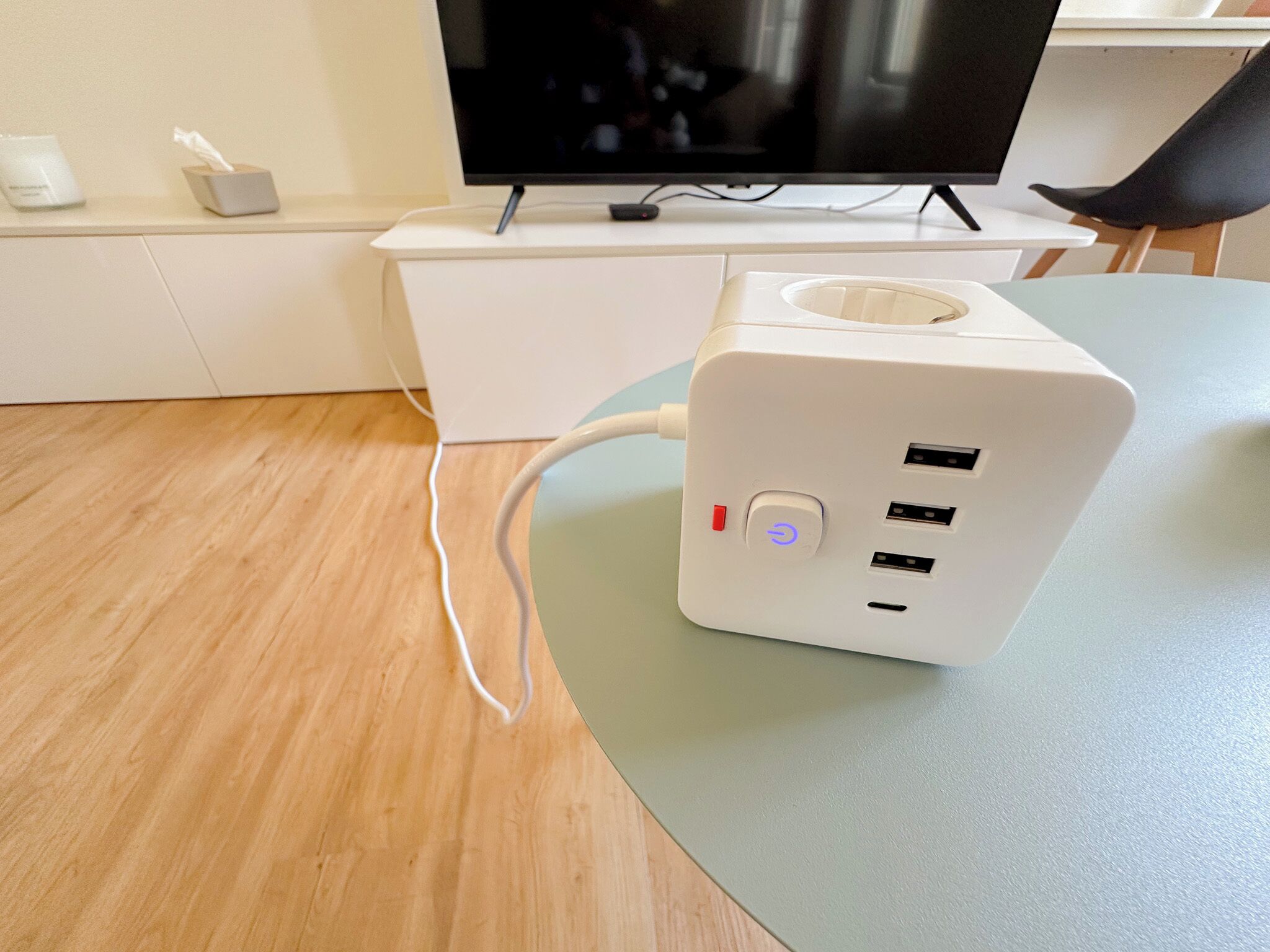 Una regleta blanca con múltiples puertos USB y un botón de encendido sobre una mesa.