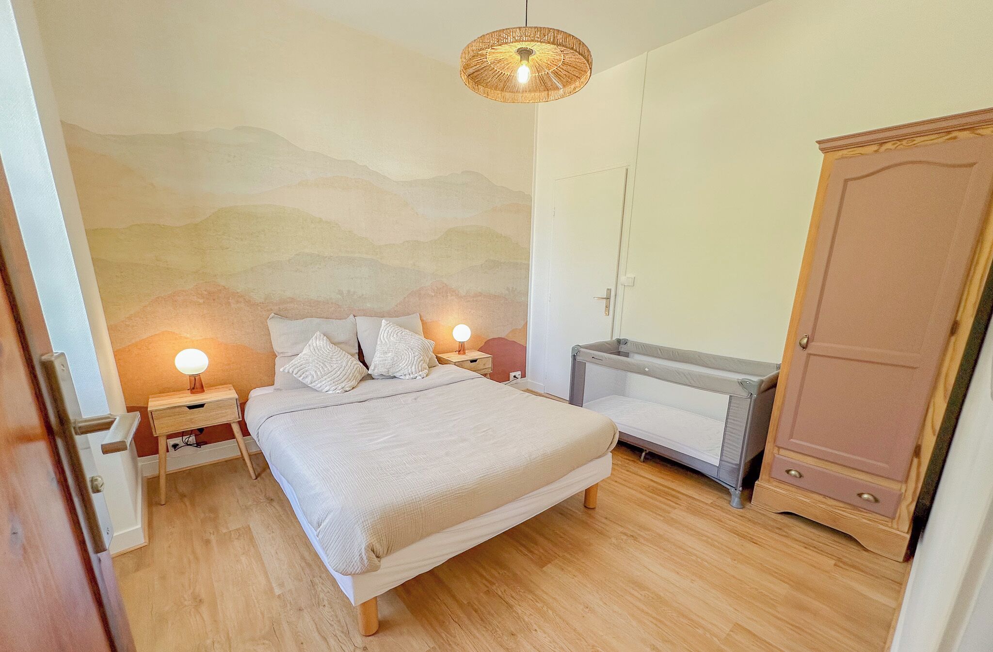 Une chambre à coucher comprenant un lit, des tables de chevet, une armoire et une fresque murale.