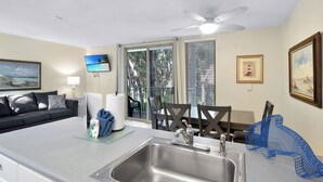 Eine moderne Küche mit Spüle aus Edelstahl, Deckenventilator und Essbereich mit Tisch und Stühlen.