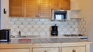 A kitchen with wooden cabinets, a microwave, a coffee maker, and a toaster.