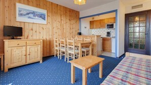 A cozy room with wooden walls, a dining area, a kitchen, and a bed.
