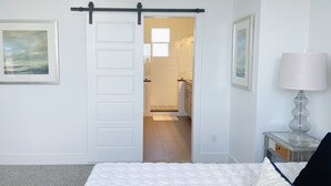 A bedroom with a bed, a nightstand with a lamp, and a sliding door leading to a bathroom. - Moonlight Retreat, near Wedding Venue & Breweries (Dripping Springs)