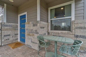 A covered patio with a stone wall, a blue door, and a table with chairs. - Moonlight Retreat, near Wedding Venue & Breweries (Dripping Springs)