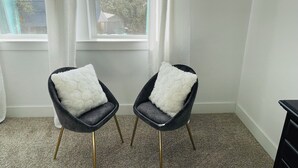 Two black chairs with white fluffy cushions, positioned in front of a window with a view of trees and buildings. - Moonlight Retreat, near Wedding Venue & Breweries (Dripping Springs)